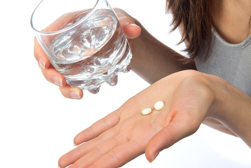 Frau nimmt Tabletten mit Wasser