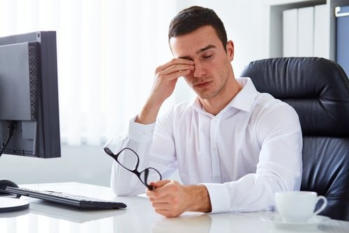Mann sitzt müde vor Computer
