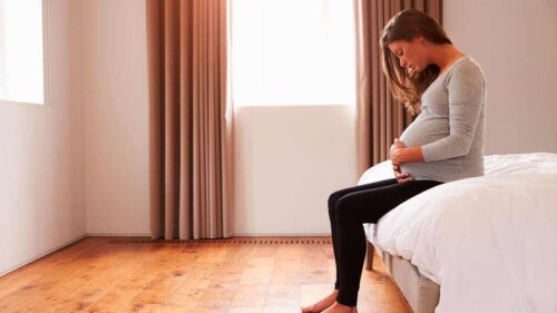 Schwangerschaft - Frau sitzt auf einem Bett