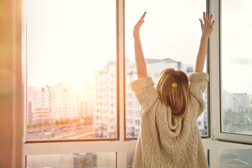 Frau streckt sich vor einem Fenster und wartet auf Veränderungen