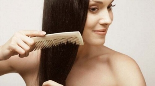 Frau kämmt Haare um Haarausfall vorzubeugen