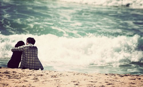 mann-sitzt-mit-seinem-hund-am-strand-vergeben