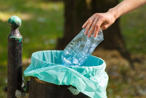 frau-wirft-plastikflasche-in-den-muell-plastik