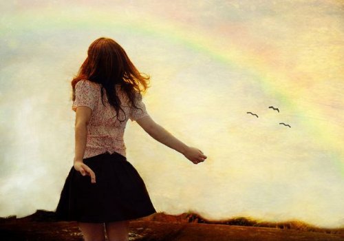 frau-schaut-in-den-himmel-mit-regenbogen-genehmigungen