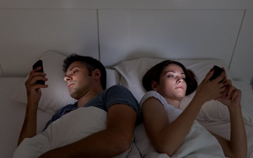 blaues Licht stört den Schlaf von Mann und Frau im Bett