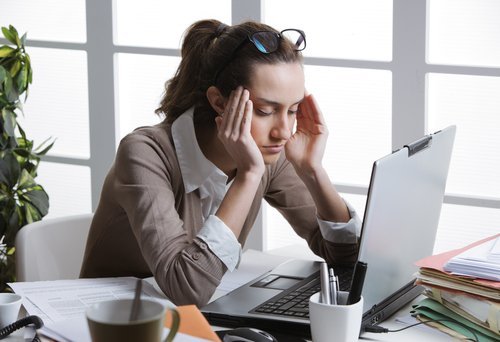 Frau am Computer hat Kopfschmerzen