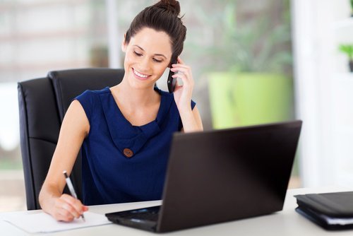 Frau am Telefon vor dem Computer