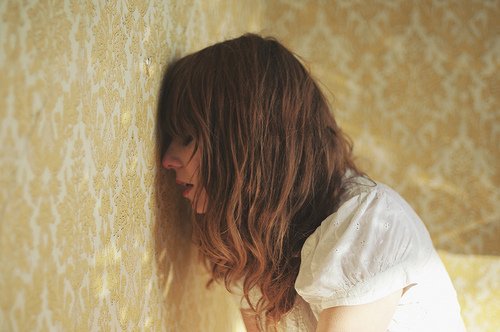 Frau lehnt Stirn an die Wand Menstruation