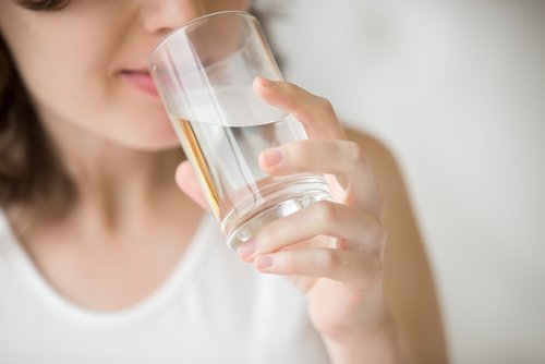 Frau trinkt Wasser gegen Krämpfe