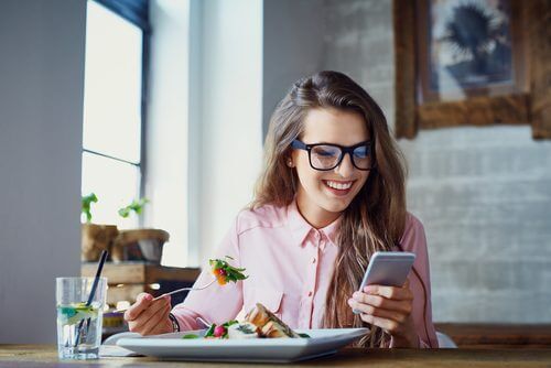 junge Frau essend und mit Handy