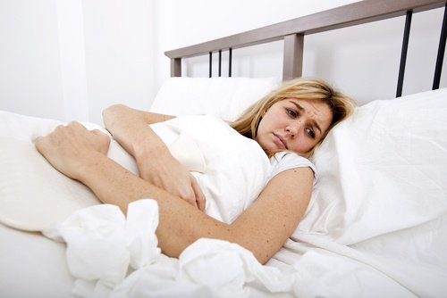 Schilddrüsenprobleme erkennen: Frau mit Schmerzen im Bett