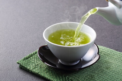 Zum Abnehmen mit grünem Tee gieße eine Tasse des heißen Getränks ein.