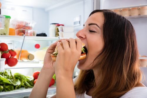 Frau isst Hamburger statt Vorteile von Chiasamen zu genießen