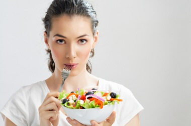 Frau isst gesunden Salat um Epigastralgie zu verhindern