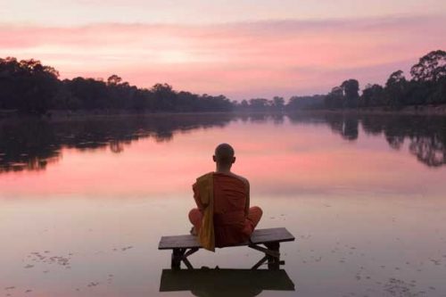 Mönch meditiert und bedankt sich mit Namaste