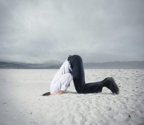 Mann steckt Kopf in den Sand, denn er hat ungelöste Probleme