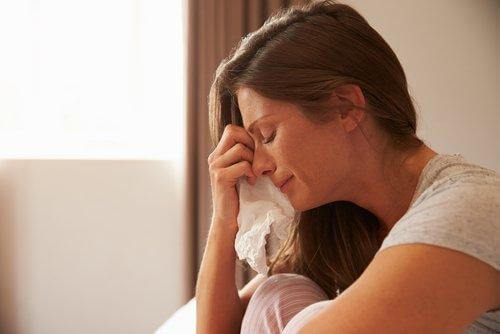 Eine Frau wischt sich mit einem Taschentuch die Tränen aus dem Gesicht.