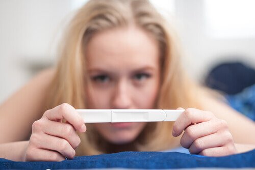 Eine Frau hält einen Schwangerschaftstest, nachdemm sie mit Hilfe der Nachtkerze versucht, schwanger zu werden.