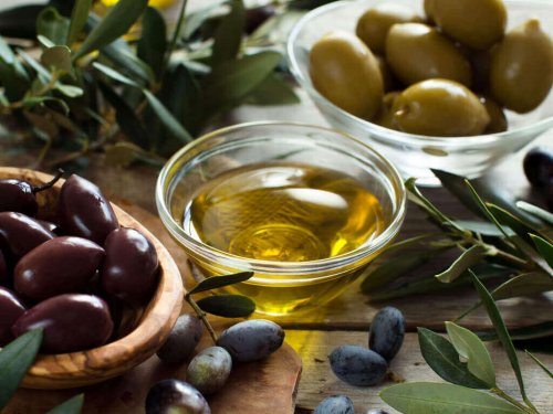 Eine Schale mit Olivenöl steht neben einer Schale gefüllt mit Oliven.
