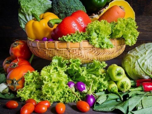 Viele verschiedene Gemüsesorten in und vor einem Korb, wie Paprika, Salat, usw.