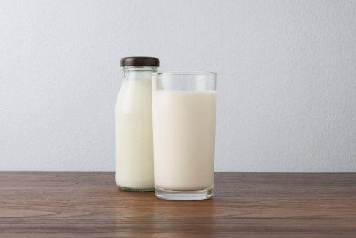 Auf einem Tisch stehen ein Glas und eine Flasche voller Molkenprotein.