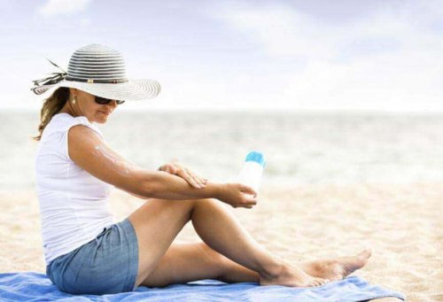 Eine Frau sitzt am Strand und trägt Sonnenschutzcreme auf.