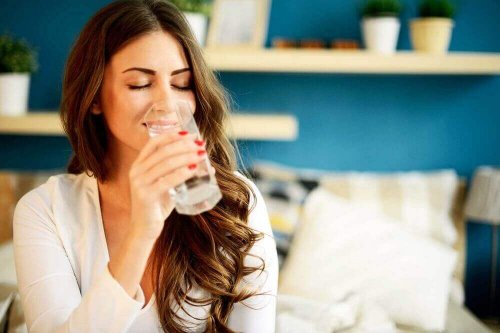 Eine Frau hat ihre Augen geschlossen und trinkt ein Glas Wasser.