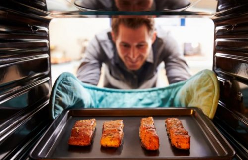 Mann holt Lachs aus dem Ofen