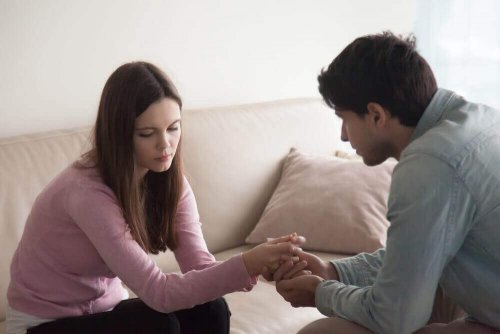 Ein Paar sitzt auf einer Couch und spricht miteinander, denn Probleme, die deine Beziehung beeinflussen, sollten besprochen werden. 