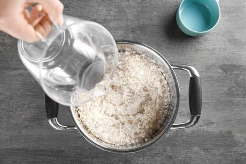 Etwas Wasser wird in einen Topf mit Reis gegossen.