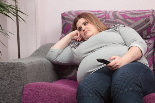 Eine an Fettleibigkeit leidende Frau sitzt auf einer Couch.