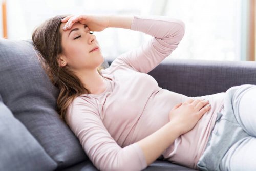 Eine Frau mit liegt mit Bauchschmerzen auf der Couch.