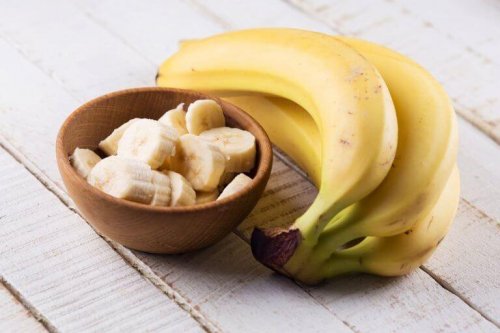 Eine Schale mit aufgeschnittenen Bananen, neben der ganze Bananen liegen.