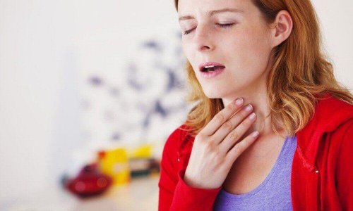 Eine Frau mit Atembeschwerden hält sich den Hals.