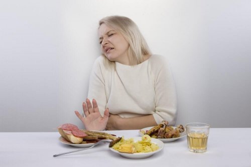 Eine Frau mit Bauchschmerzen möchte das Essen auf dem Tisch nicht essen.