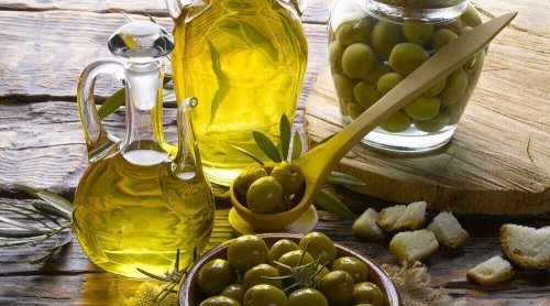 Oliven in einer Schüssel und Olivenöl in zwei Flaschen.