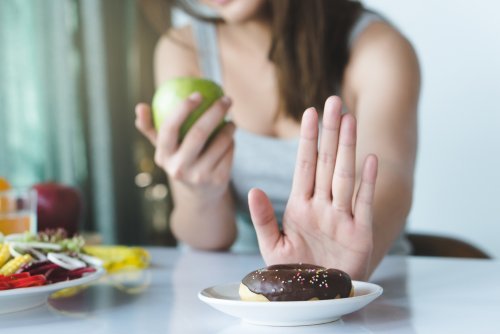 Frau verzichtet auf Donut und isst Apfel