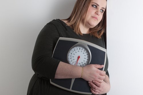 Deprimierte Frau mit Waage im Arm