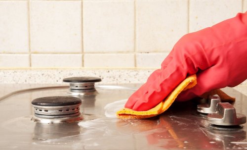 Herd wird mit Küchenlappen und Gummihandschuhen geputzt