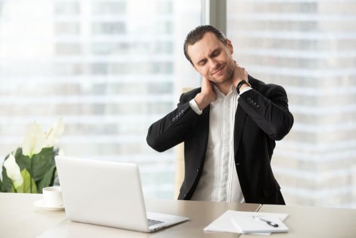 Mann im Büro hat steifen Hals