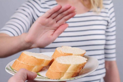 Eine Frau lehnt einen Teller mit weißem Brot ab.