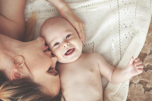 Mutter küsst ihr lachendes Baby