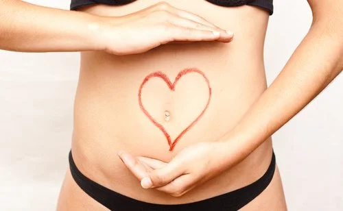 Nahaufnahme vom Bauch einer Frau, auf den ein Herz gezeichnet wurde.