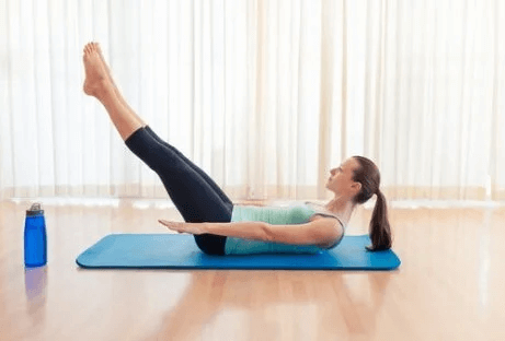 Eine Frau macht Übungen für einen knackigen Po, wie etwa die Beine anzuheben.