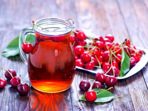 Kirschsaft, neben dem einige Kirschen liegen.