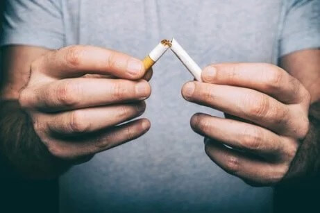 Ein Mann bricht eine Zigarette auseinander, um mit dem Rauchen aufzuhören.