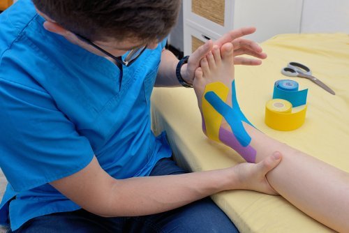 Physiotherapeut legt Bandage am Fuß an