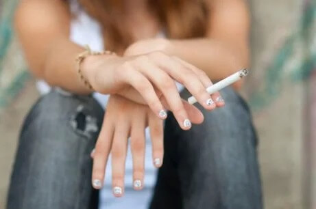 Eine Frau hält eine Zigarette zwischen ihren Fingern.