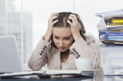 Eine verzweifelte Frau sitzt in der Arbeit vor ihrem Schreibtisch.
