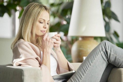 Eine Frau sitzt auf einer Couch und trinkt Tee.